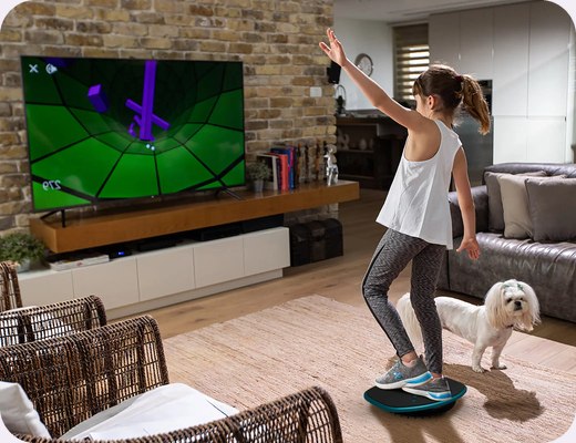 A girl playing a GoBalance game in front of the TV
